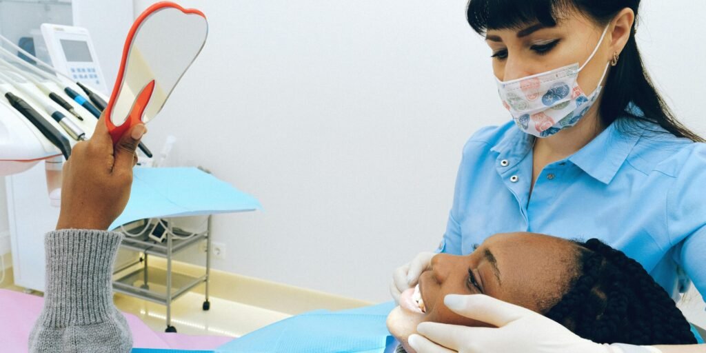 Dentist assisting a happy patient checking her smile in a mirror during a dental appointment.