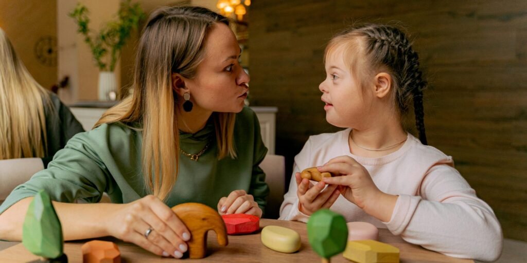 An adult woman and a child with Down syndrome engaging in playful interaction with wooden toys indoors.