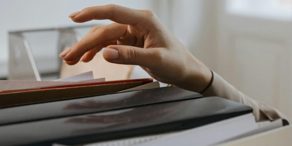 Close-up of a hand reaching into a file drawer in an office, signifying organization and archiving.