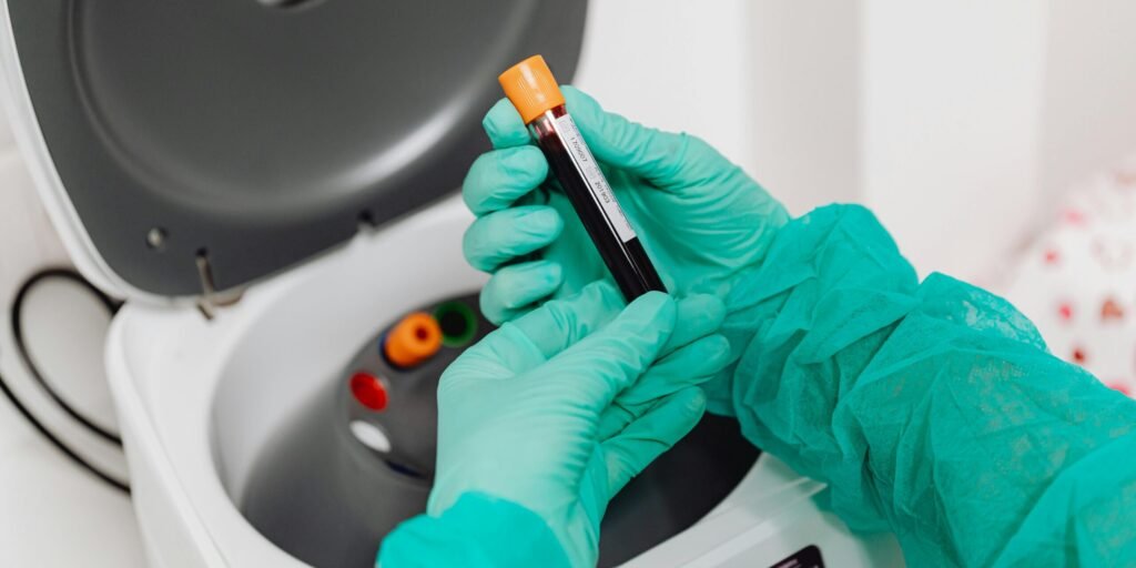 Laboratory scene with a healthcare professional preparing a blood sample for analysis using a centrifuge.