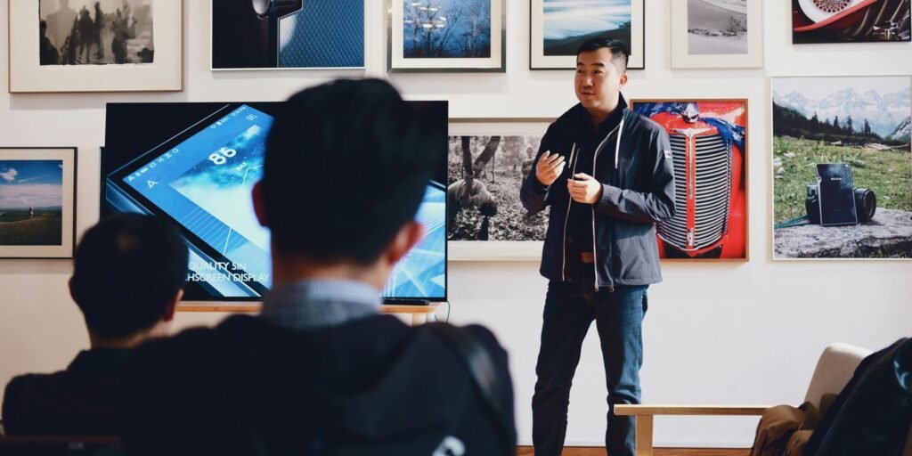 Man giving a presentation in a modern art gallery setting, engaging audience.