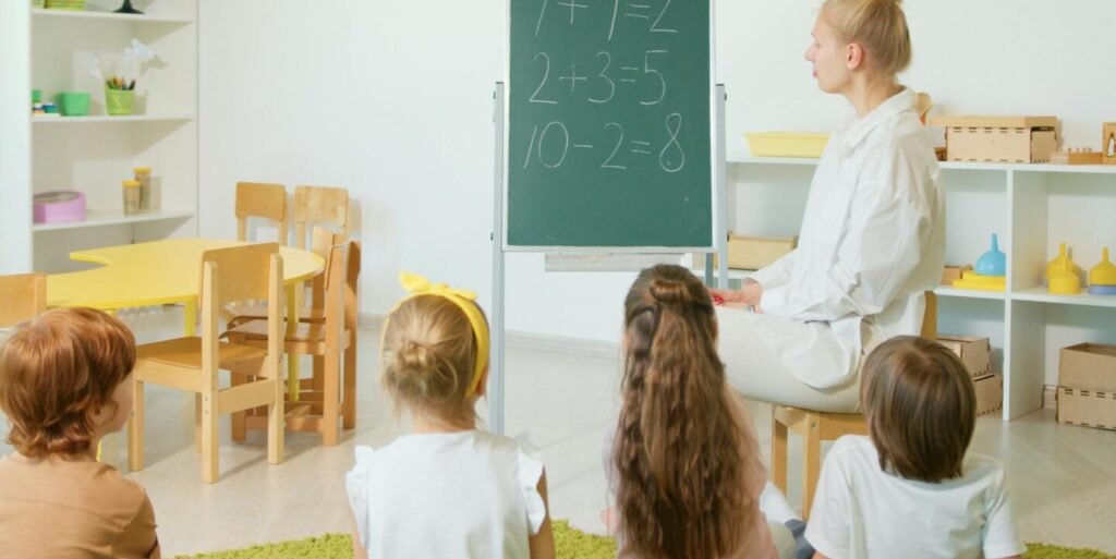 Children sitting in a colorful classroom learning basic math from a teacher.