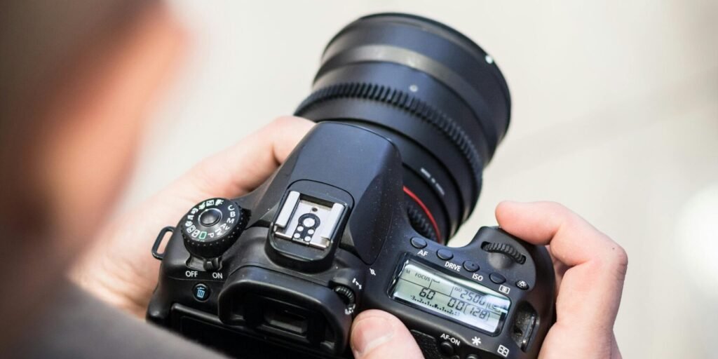 Person adjusting DSLR camera settings indoors for photography.